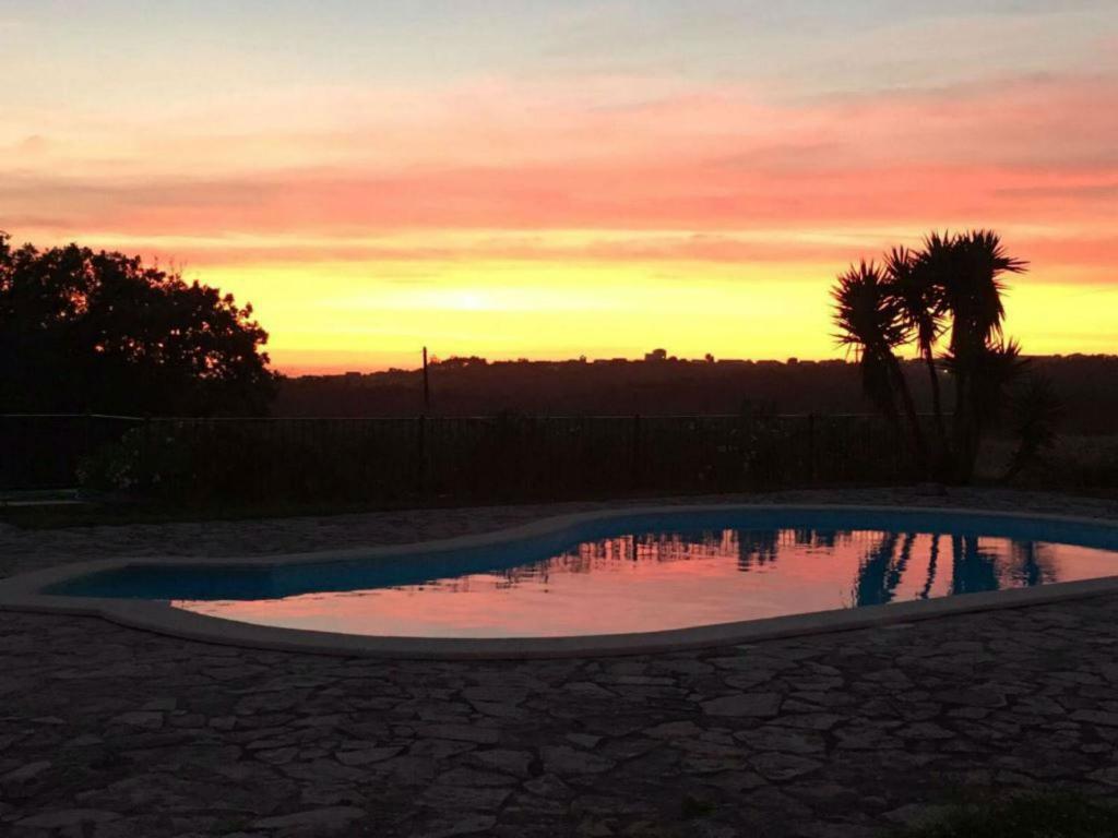a swimming pool with a sunset in the background at Casa do Cabeço in Benedita
