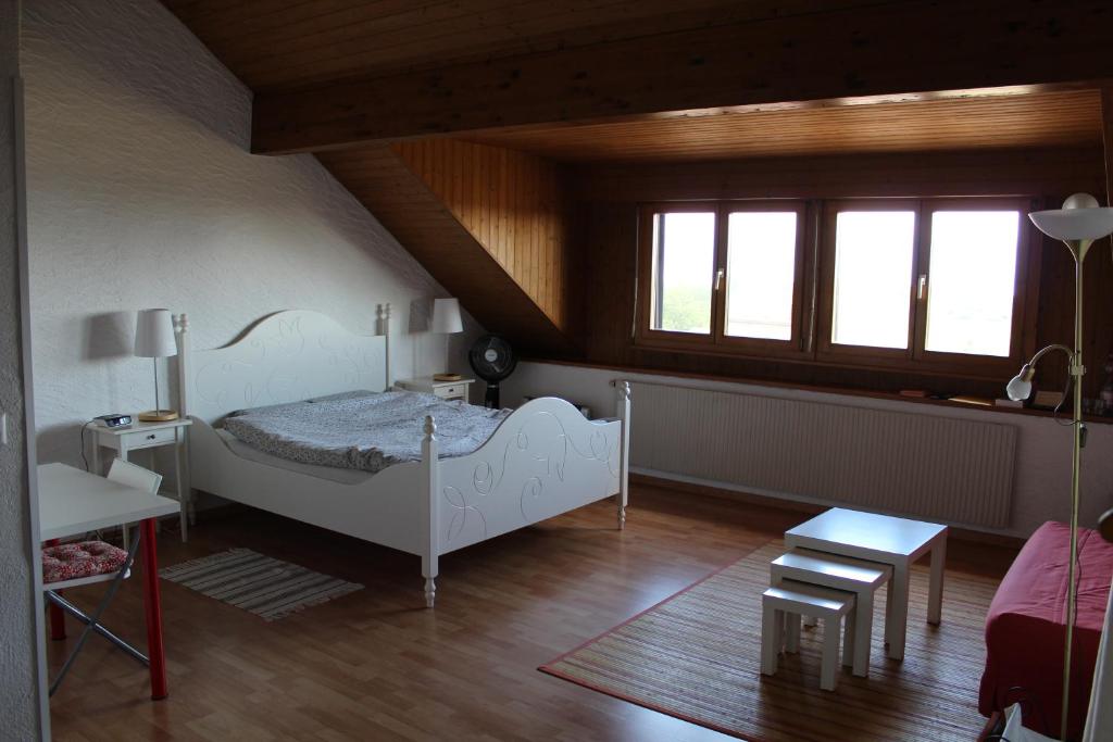 sypialnia z łóżkiem, stołem i oknami w obiekcie Bed & Breakfast Bursins w mieście Bursins