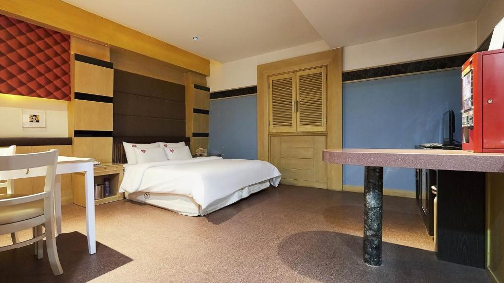 a bedroom with a bed and a desk and a kitchen at 프롬에이치 아모레미오 더클래식 수원역 in Suwon