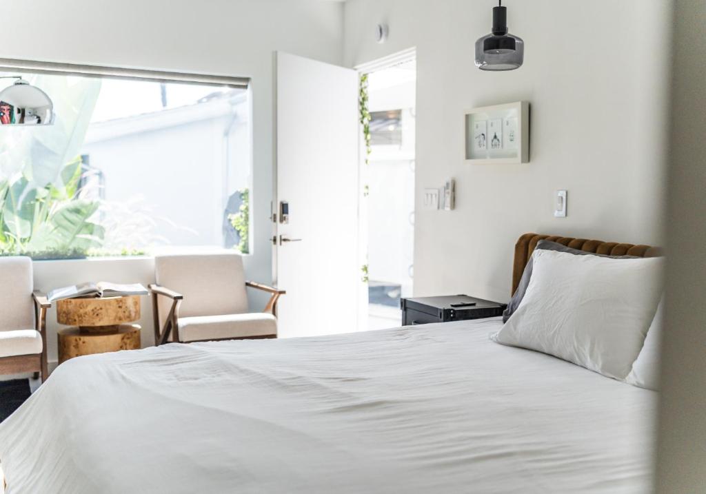 a bedroom with a white bed with two chairs at Simple La Jolla Epic bungalow #1 in San Diego