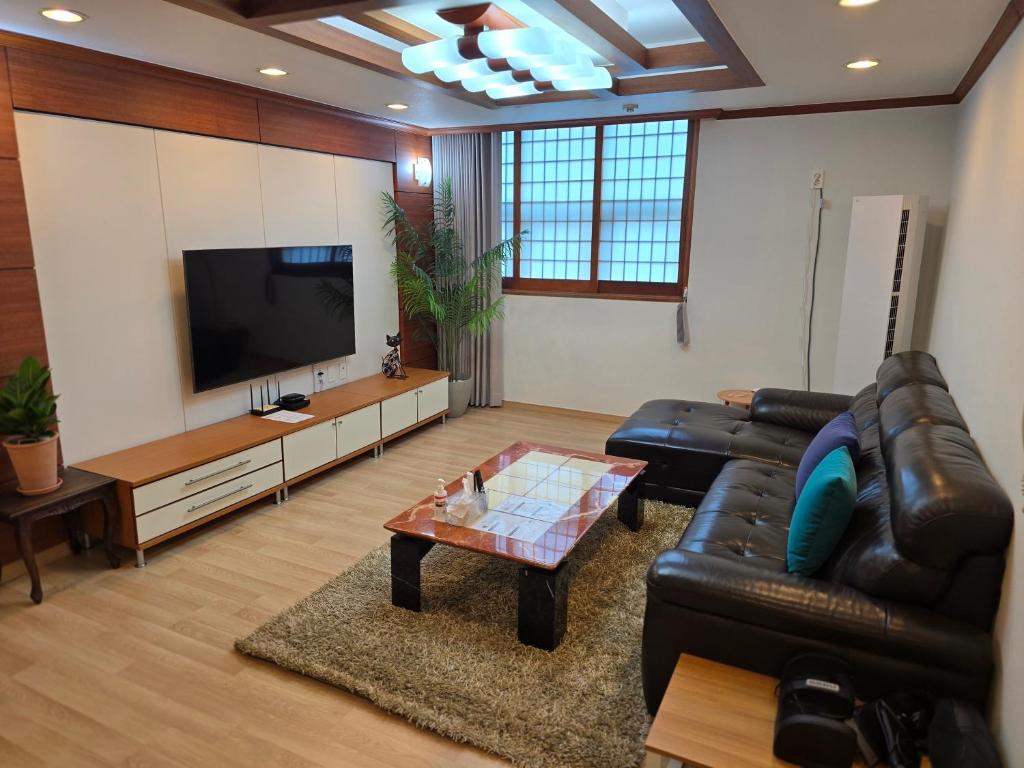 a living room with a black leather couch and a flat screen tv at 따뜻한 구미 금오산 감성하우스, 50평 단독으로 사용하는 Holiday house in Namt'ong-dong