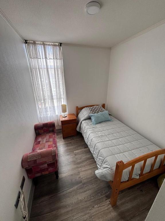 a bedroom with a bed and a chair and a window at Espectacular Depto en Cavancha in Iquique
