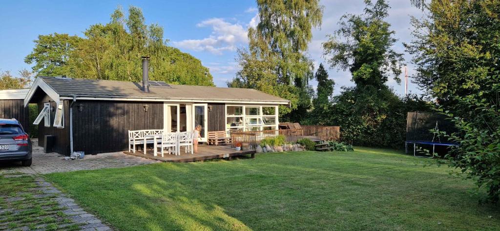 a small shed with a table and chairs in a yard at Lovely Bright Summer House Close To The Beach in Rødvig