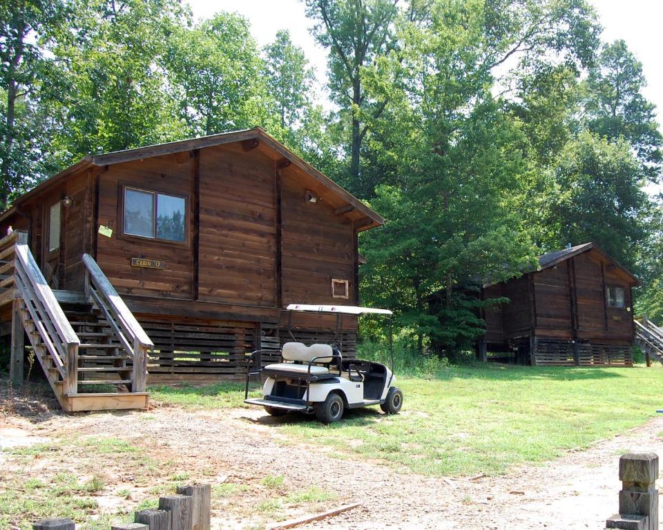 una pequeña cabaña con un coche aparcado delante en Forest Lake Camping Resort Cabin 18, en Freewood Acres