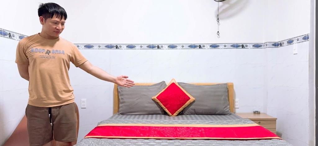 Un homme est debout à côté d'un lit dans l'établissement Phương Anh 2 - Hotel Bình Tân, à Hô-Chi-Minh-Ville
