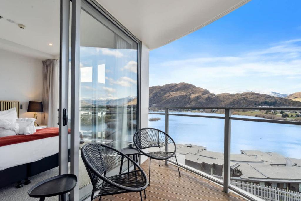 a bedroom with a balcony with a view of the water at Sunlit Serenity Lakefront Apartment in Frankton
