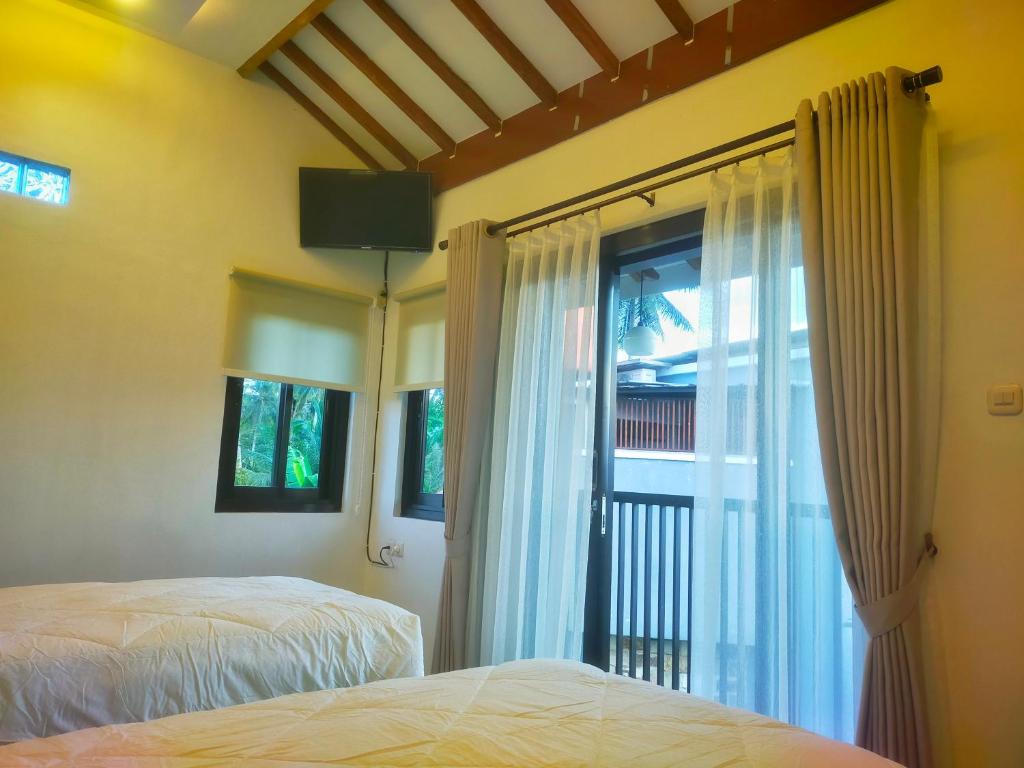 a bedroom with two beds and a window at AUREIRIN Guesthouse in Banyuwangi