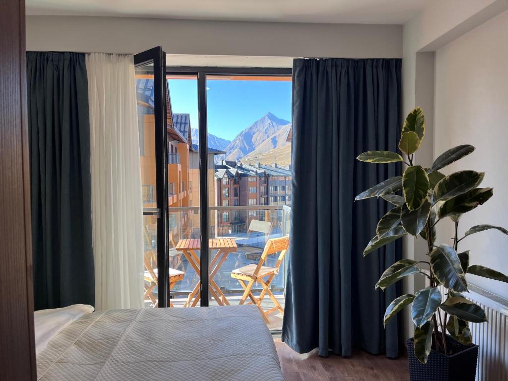 Un dormitorio con una cama y vista a un balcón. en Cozy apartment next to ice rink, en Gudauri
