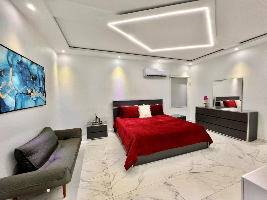 a bedroom with a red bed and a couch at FYV Beach Villas in San Juan