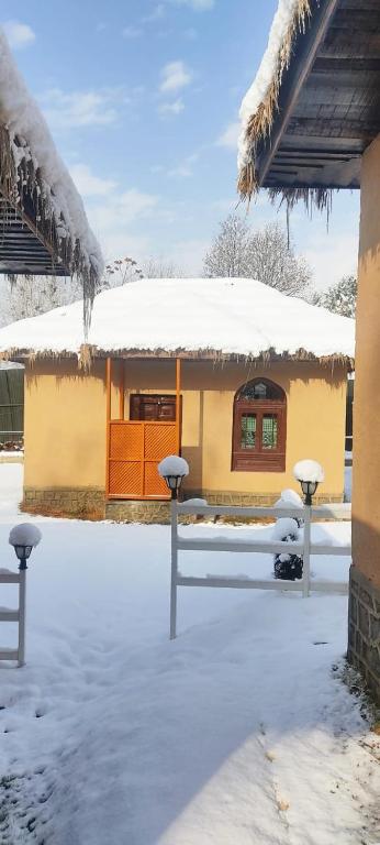 a house with a snow covered roof and a building at Kulube cottages and restaurant in Kijapāra