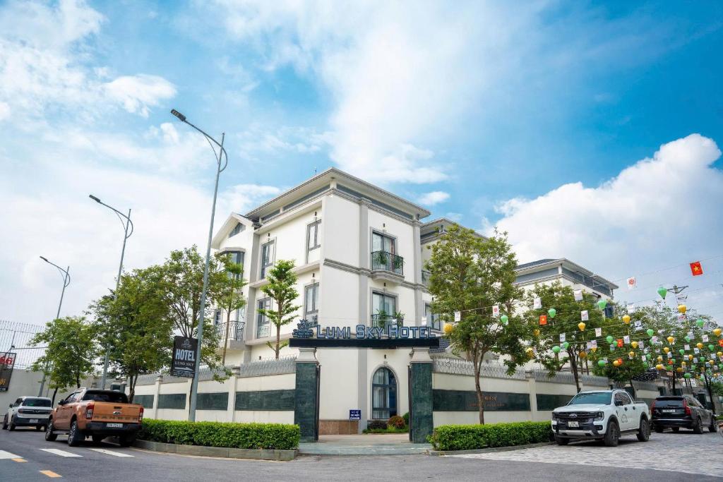 un bâtiment blanc avec des voitures garées devant dans l'établissement Lumi Sky Hotel - by BAY LUXURY, à Hà Ðông
