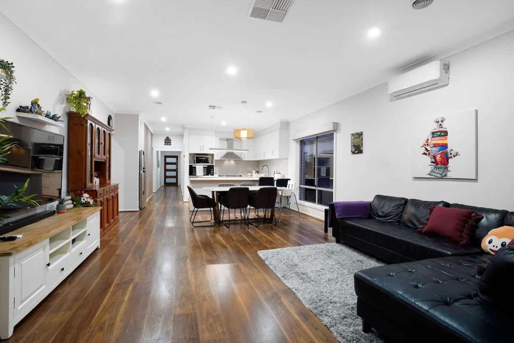 Una sala de estar con un sofá negro y una cocina. en Family Home with Home Theater in Tarneit, en Tarneit
