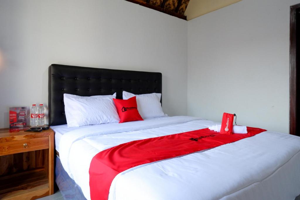 a bedroom with a large bed with red pillows at RedDoorz @ Kampoeng Etnik Kebumen 2 in Kebumen