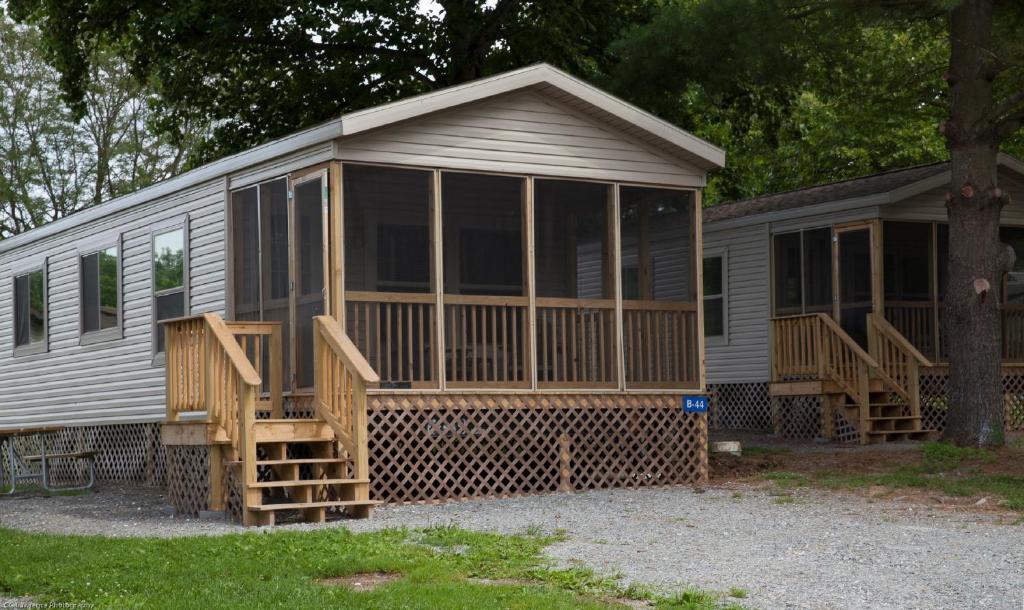 a screened in cabin with a porch and a deck at Circle M Camping Resort Screened Park Model 27 in Wabank