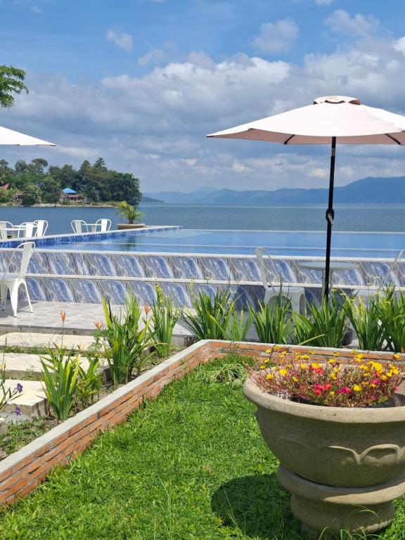 eine Terrasse mit einem Sonnenschirm und Blumen in einem Blumentopf in der Unterkunft Juma cottages in Tuk Tuk