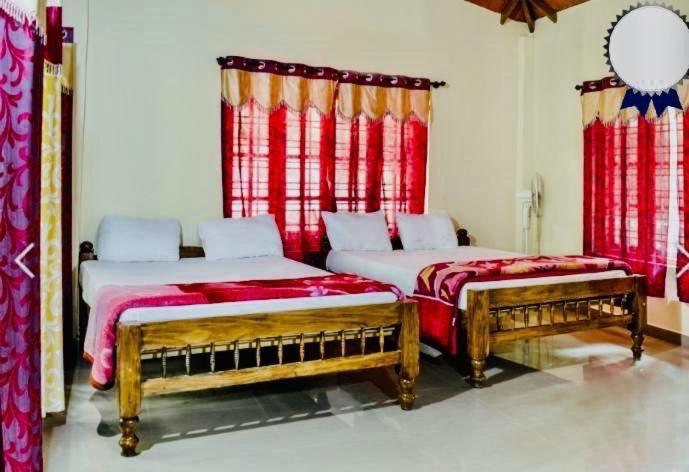 two beds in a room with red curtains at New Garden View in Madikeri