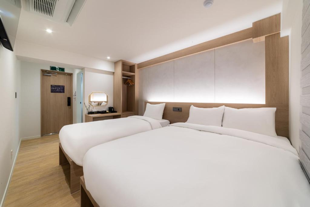 two beds in a hotel room with white sheets at Hi Stay Jongno in Seoul