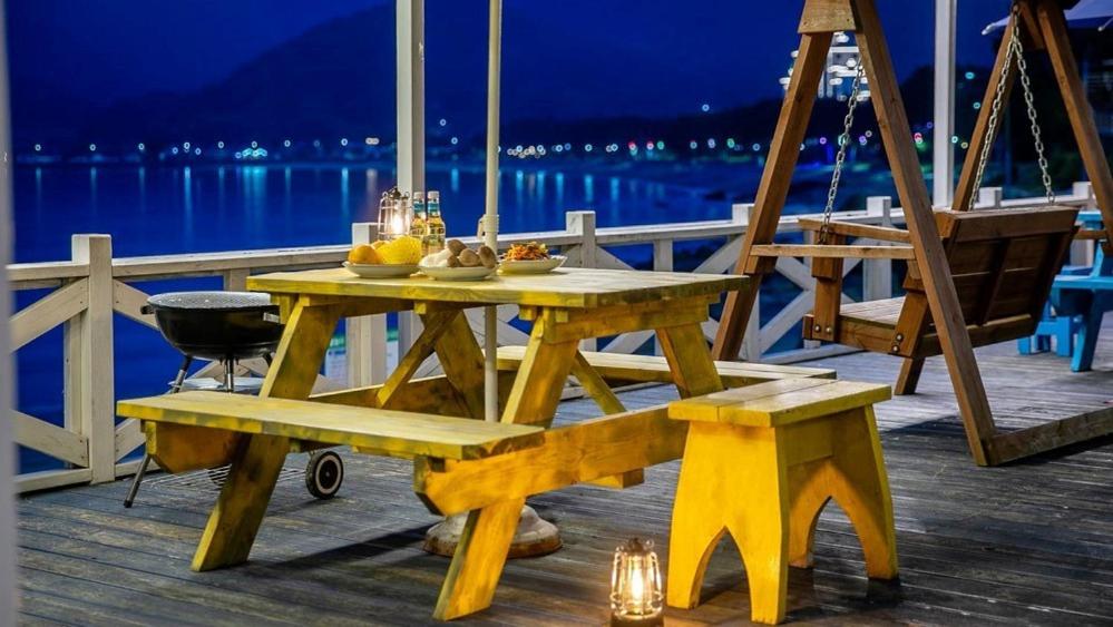a picnic table on a deck with a view of the water at Namhae Melody Kids Private Pension in Sukho