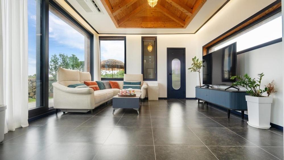 a living room with a couch and a table at Seogwipo Pyoseon Doldamjip in Pyoseon