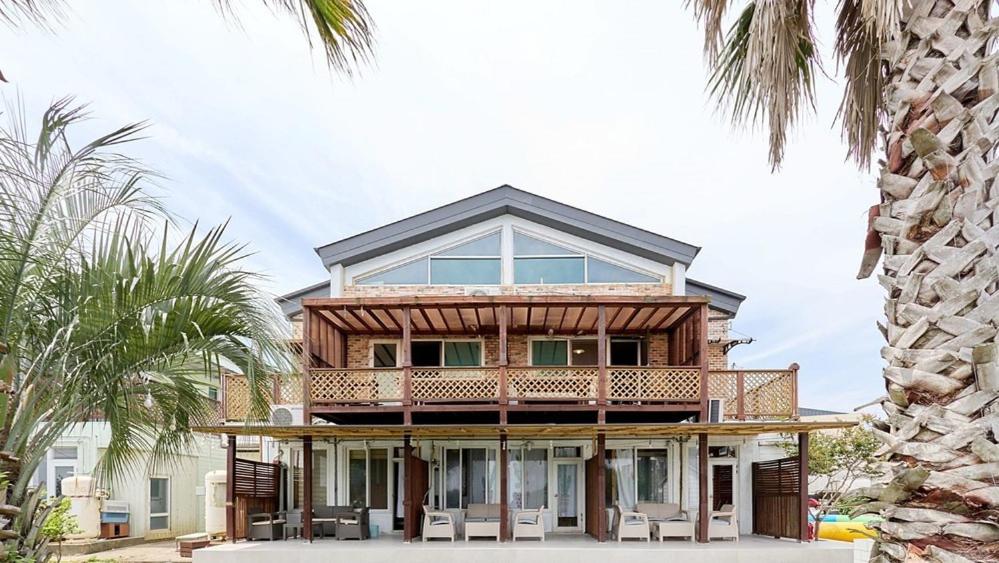 a house with a wrap around porch with a deck at Seogwipo From Jeju in Kama-ri