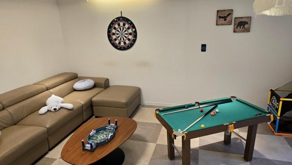 a living room with a couch and a pool table at Chuncheon Gangchon Luna Pension in Kugong-ni