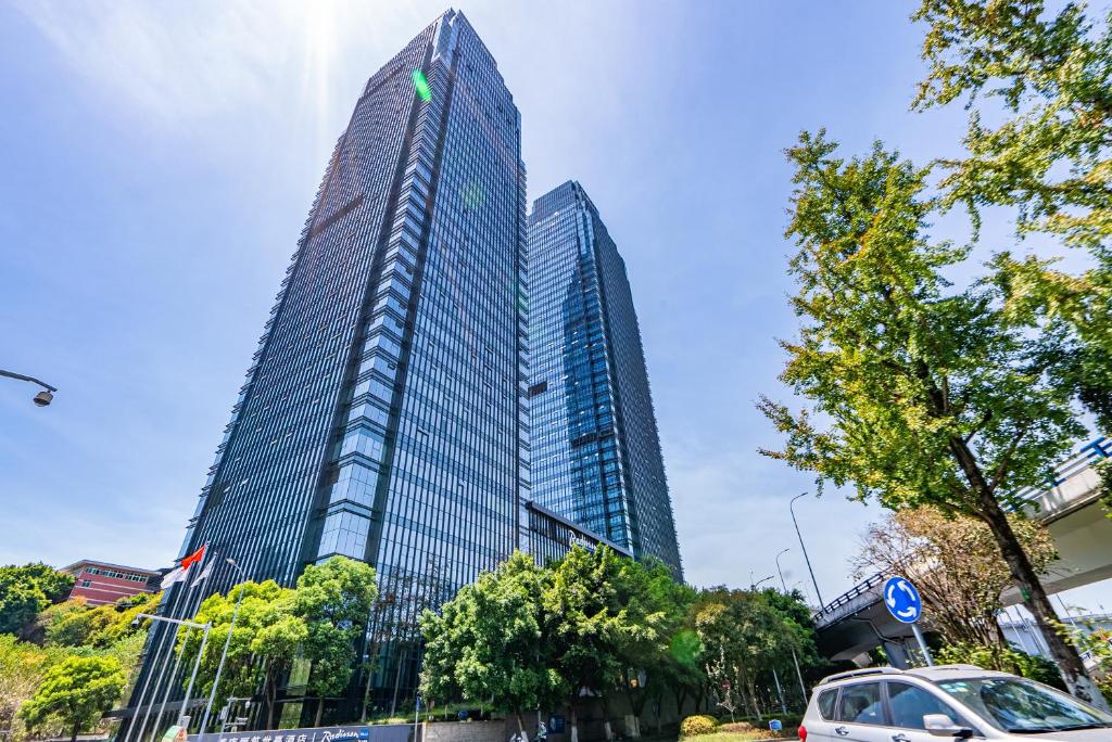 een hoge wolkenkrabber met een auto ervoor geparkeerd bij Aixin Yangtze River International Apartment in Chongqing