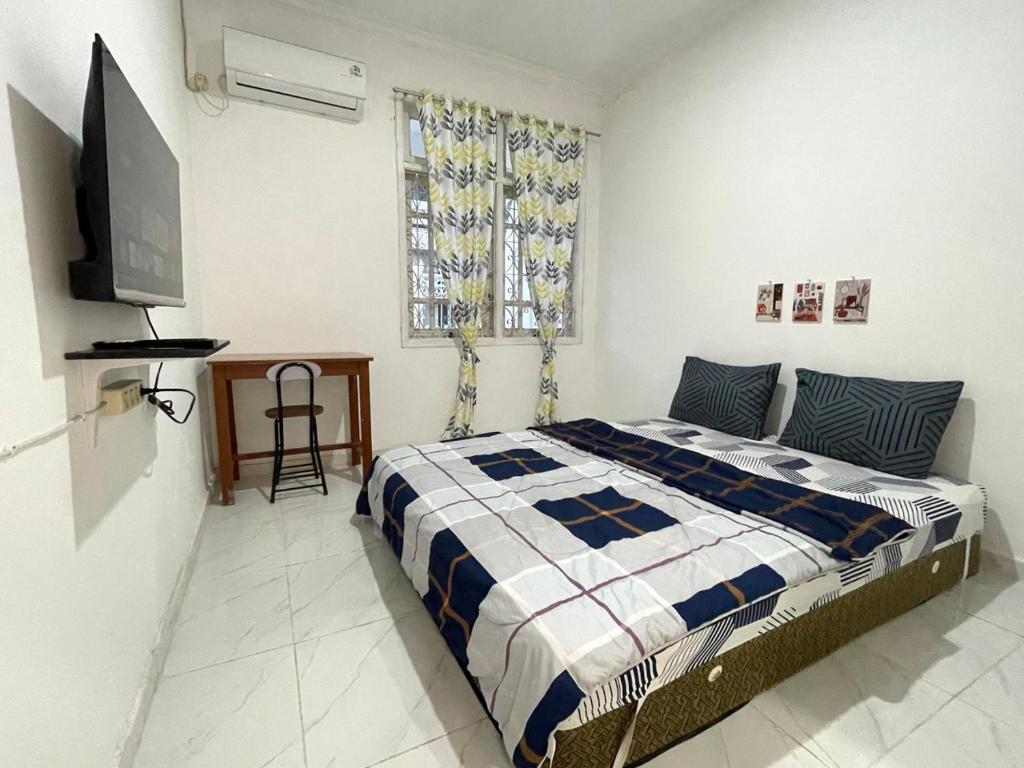 a bedroom with a bed and a flat screen tv at Dehome Suko Syariah in Surabaya