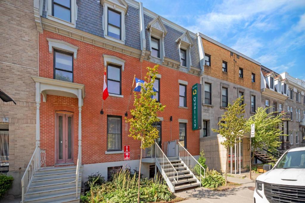 a red brick building with flags in front of it at Quality Inn Centre-Ville in Montréal