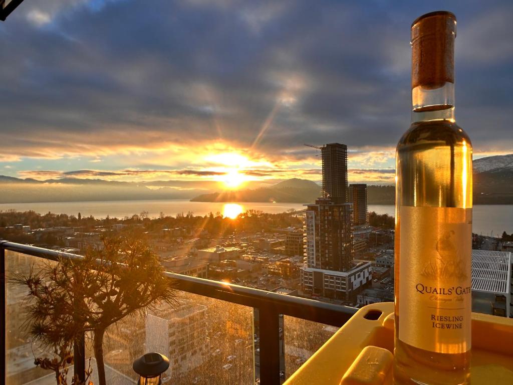 a bottle of wine sitting on a table with the sunset at One Million-Dollar Vista Premium 2-Bed Sky Flat with Lake & City Views in Kelowna