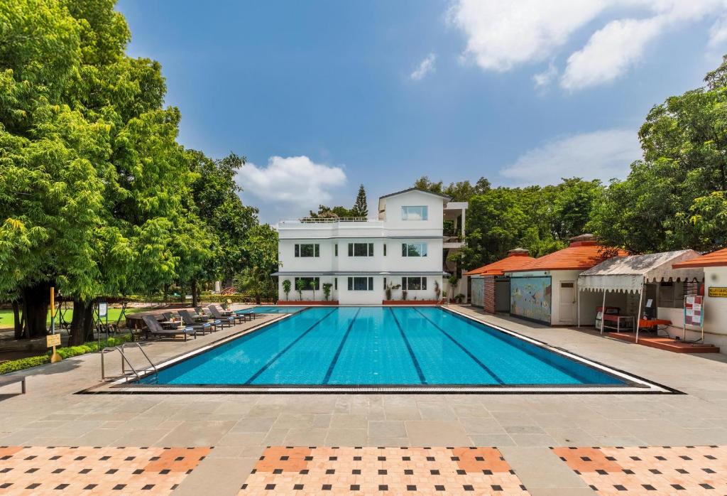 Una piscina vacía frente a una casa blanca en Amantra Shilpi Resort & Spa Udaipur, en Udaipur