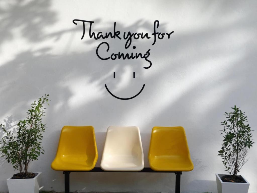 two yellow chairs against a wall with a thank you for coming sign at หลังเขาโฮมสเตย์ เกาะลิบง in Ko Kwang
