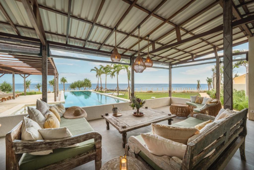 un soggiorno all'aperto con tavolo, sedie e piscina di Naluna Lembongan a Nusa Lembongan