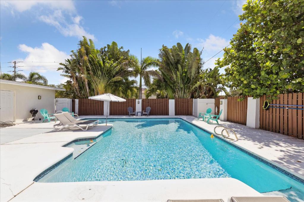 a swimming pool with chairs and an umbrella at 308 Formosa Drive in Cocoa Beach