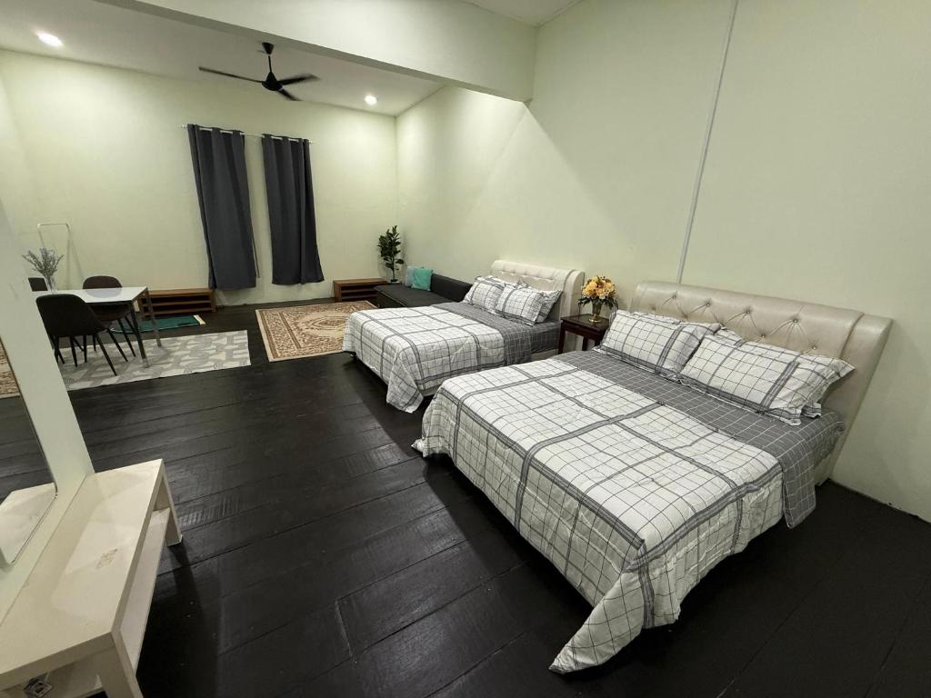 a bedroom with two beds and a dining room with a table at cozy nest panji in Kota Bharu