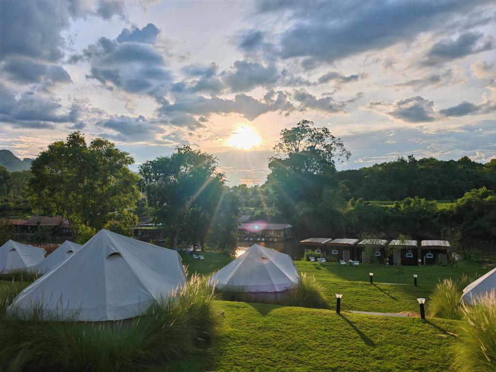 a group of tents in a field with the sunset at Rivendale in Ban Gaeng Cho