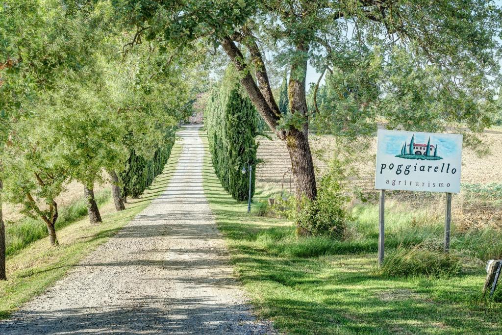 a tree lined road with a sign on the side at Agriturismo Il poggiarello in Foiano della Chiana