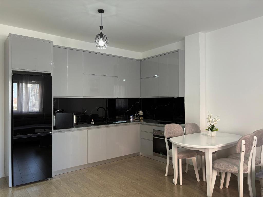 a kitchen with white cabinets and a table and chairs at Mme apartment in Kamëz