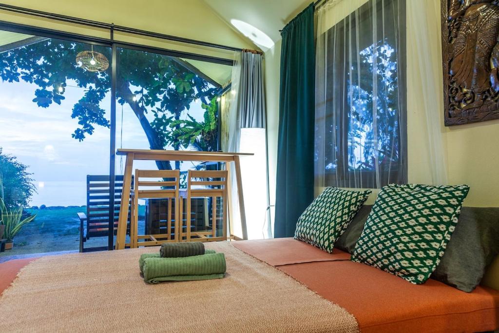 a living room with a couch and a large window at Beach front cottage in Haad Pleayleam