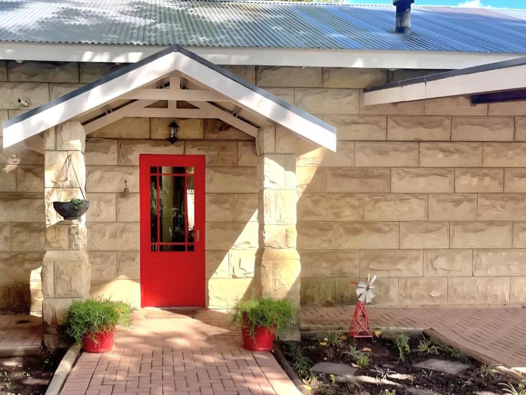 a red door on a house with a brick wall at Bella Rosa Cottage in Clarens