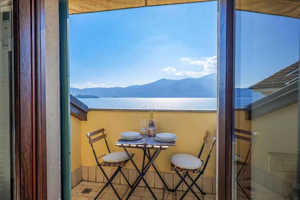 Una mesa y sillas en un balcón con vista al agua. en Casa Motti, en Verbania