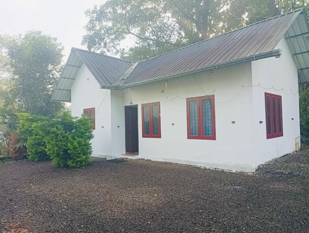 a white house with red windows and a garage at Munnar Hills And Mist Views in Anachal