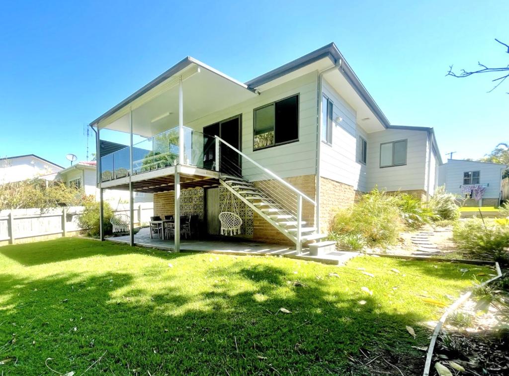 a house with a staircase in a yard at Seaside Escape - 5 BR 2 Kitchens in Port Macquarie