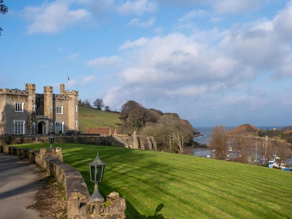 un viejo castillo en una colina con un campo verde en Watermouth Castle, Harbour Apartment, en Ilfracombe