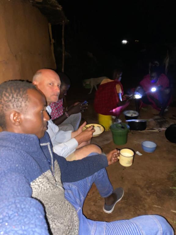 a group of people sitting on the floor with cups at Maasai village home stay in Sekenani