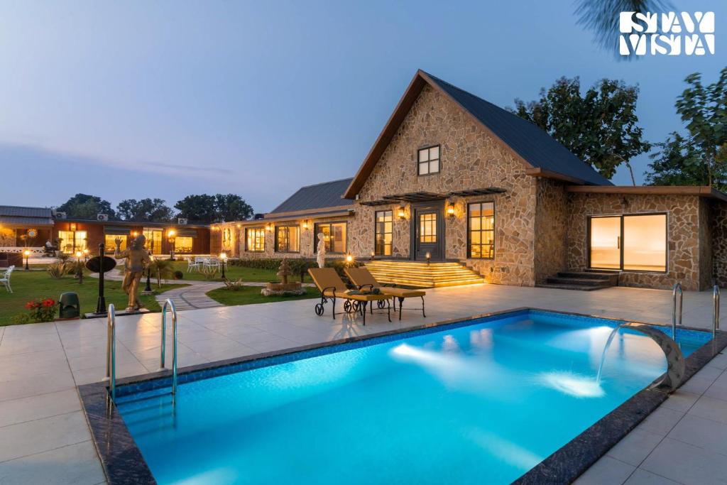 a large swimming pool in front of a house at StayVista at The Harbhson House with Pool, Jacuzzi, Sauna room, Woodfire Pizza, Projector in Bidauli