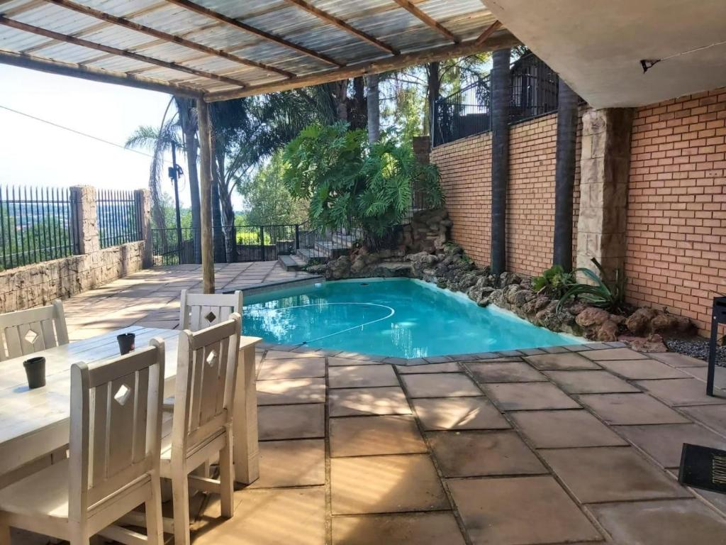 une piscine dans un patio avec deux chaises dans l'établissement Sunset Cottage - Own Water - Own Electricity, à Pretoria