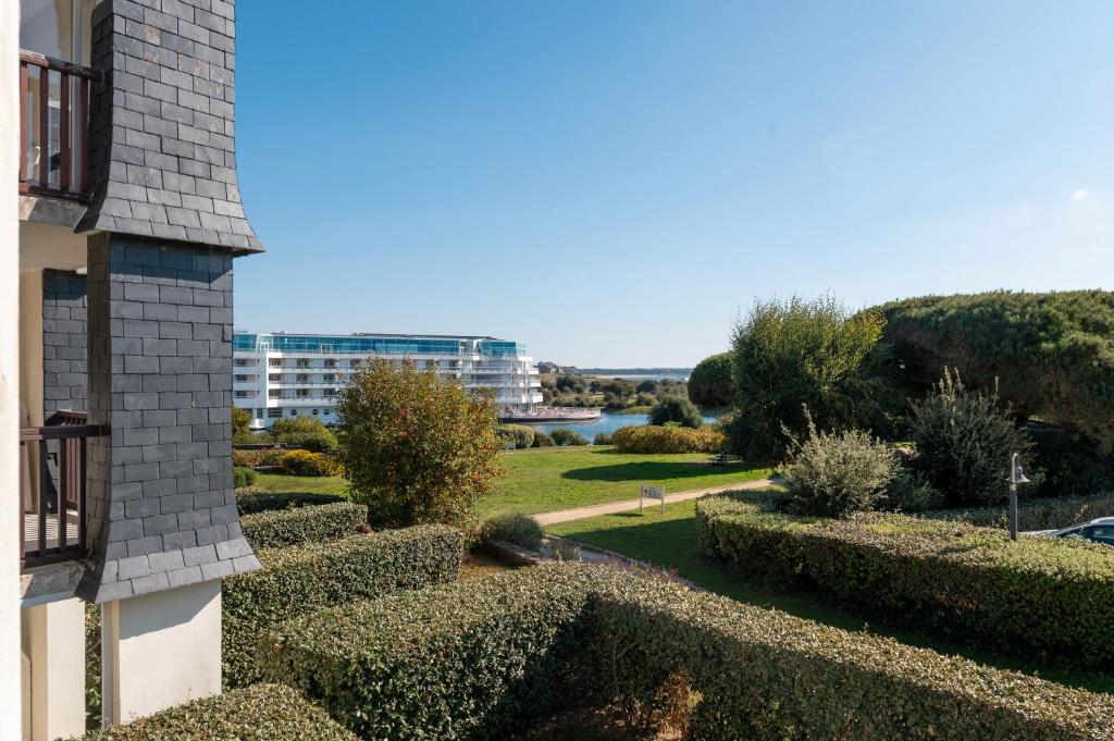 a view of a garden with bushes and a building at L'Océanic vue mer, Draps et parking in Arzon