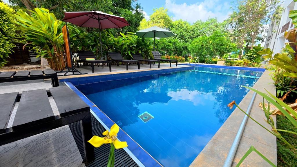 a pool with benches and umbrellas next to a building at Ananthara Resort in Anuradhapura