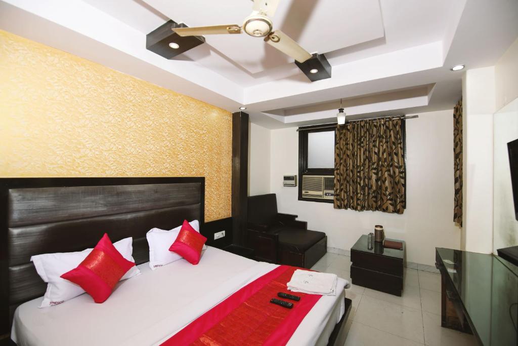 a bedroom with a bed with red pillows and a ceiling fan at Hotel Lav-kush Deluxe 2 Min From New delhi Railway Station in New Delhi