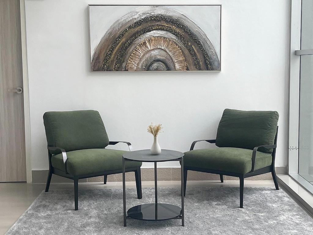 Two upholstered lounge chairs face each other across a small table by a glazed wall.
